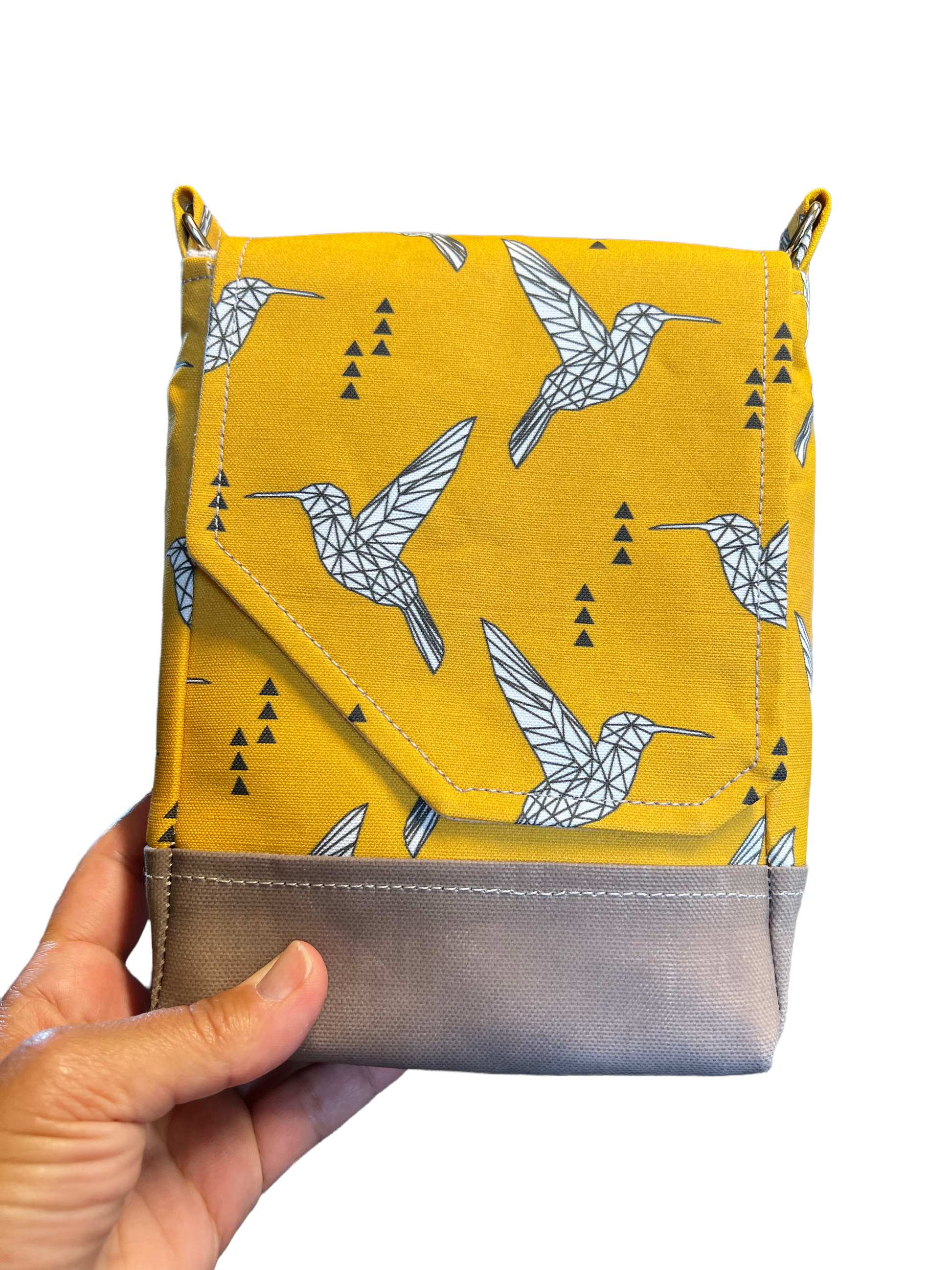 Hand holding yellow purse with bird